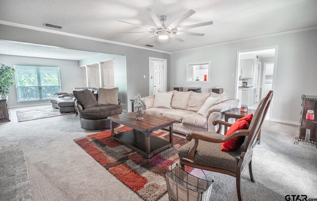 living room featuring crown molding, light colored carpet, a textured ceiling, and ceiling fan