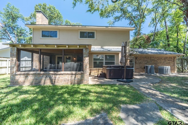 back of property with central air condition unit, a lawn, a sunroom, and a hot tub