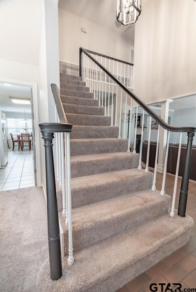 stairs featuring tile patterned floors and a notable chandelier