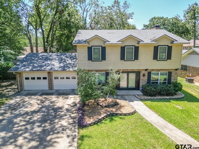 view of front of home featuring cooling unit, a garage, and a front yard