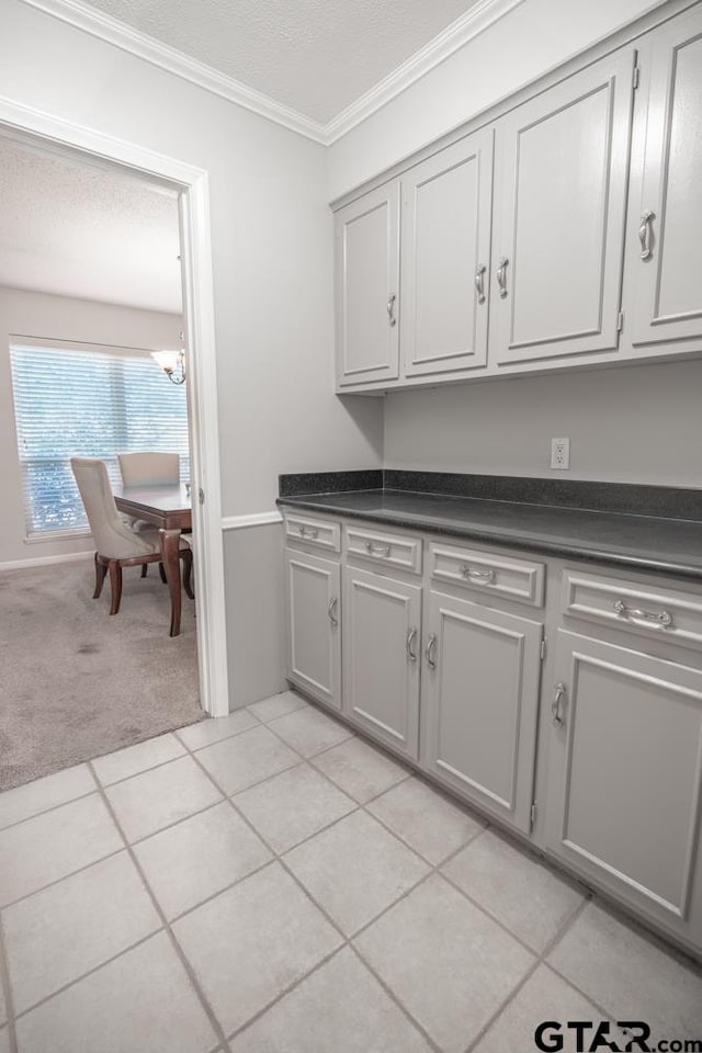 laundry room featuring a textured ceiling, light tile patterned floors, and crown molding