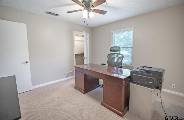 office area featuring a textured ceiling, light carpet, and ceiling fan