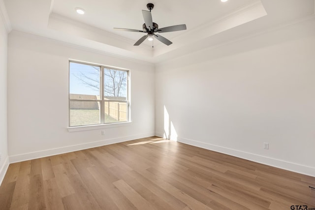 empty room with a tray ceiling and light hardwood / wood-style flooring