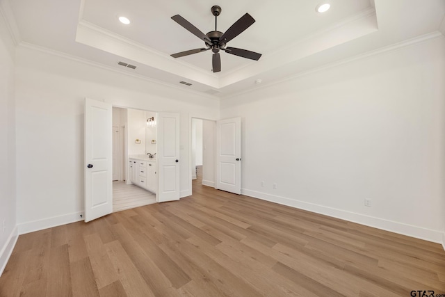 unfurnished bedroom with ceiling fan, a raised ceiling, and light hardwood / wood-style flooring