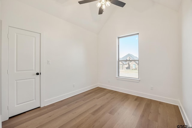 empty room with ceiling fan, vaulted ceiling, and light wood-type flooring