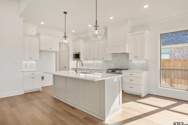 kitchen with sink, white cabinets, decorative light fixtures, and custom range hood