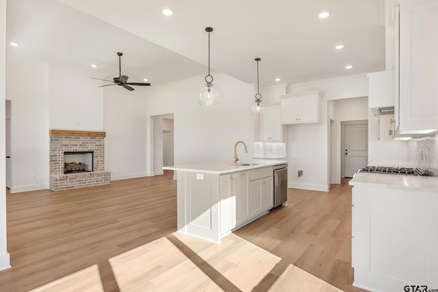 kitchen with white cabinets, ceiling fan, an island with sink, and hanging light fixtures