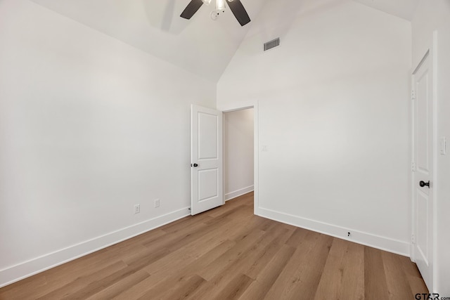 empty room featuring ceiling fan, high vaulted ceiling, and light wood-type flooring