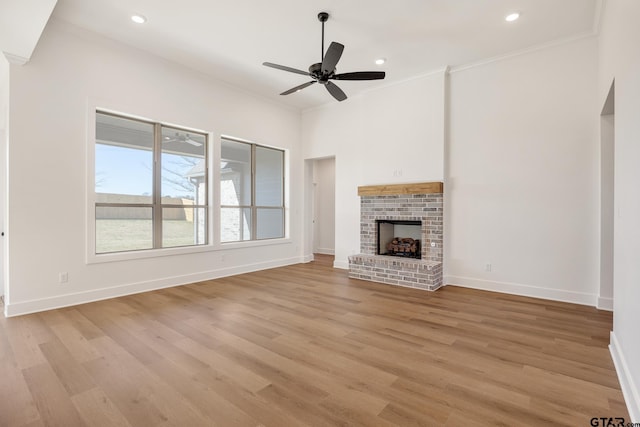 unfurnished living room featuring ceiling fan, light wood-type flooring, ornamental molding, and a brick fireplace