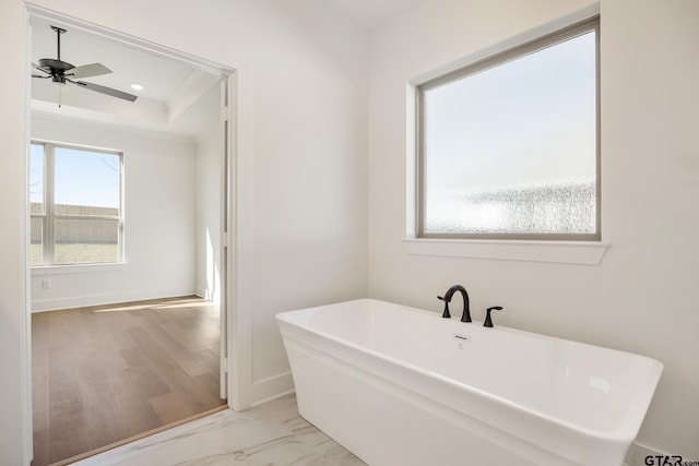 bathroom featuring ceiling fan, crown molding, and a bath