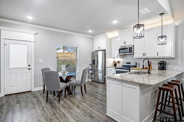 2609 Tulsa St, Tyler, TX 75702 - kitchen with appliances with stainless steel finishes, decorative backsplash, wood finished floors, a kitchen bar, and ornamental molding
