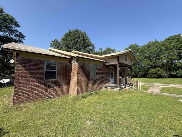 view of front of home with brick siding, metal roof, and a front yard