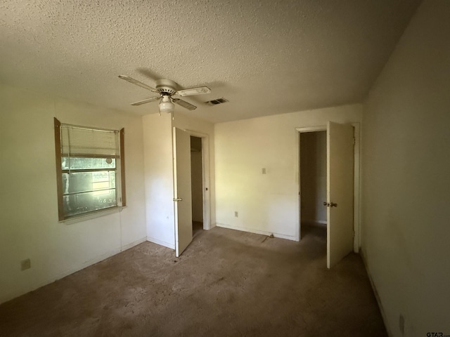 unfurnished bedroom featuring a textured ceiling, visible vents, carpet flooring, and ceiling fan
