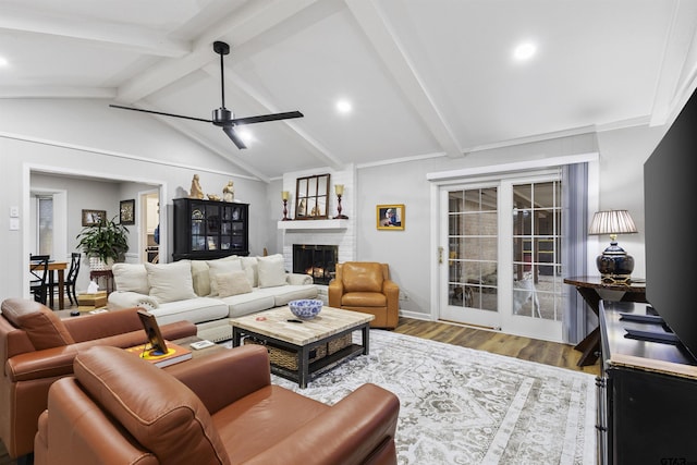 living room featuring ceiling fan, a fireplace, lofted ceiling with beams, and light hardwood / wood-style flooring