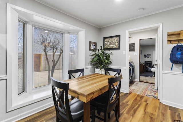 dining room with washer / clothes dryer, ornamental molding, and hardwood / wood-style floors