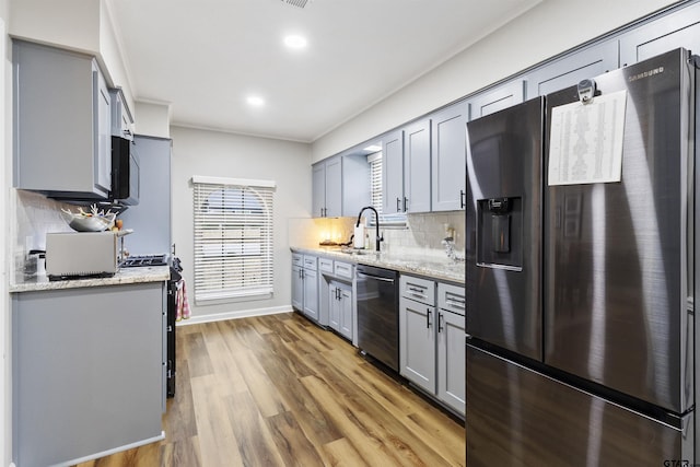 kitchen with sink, stainless steel fridge, gray cabinets, dishwasher, and light stone countertops