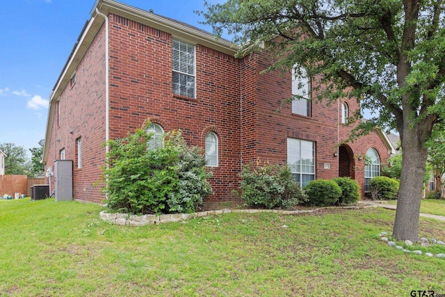view of front of home with central air condition unit, brick siding, and a front yard