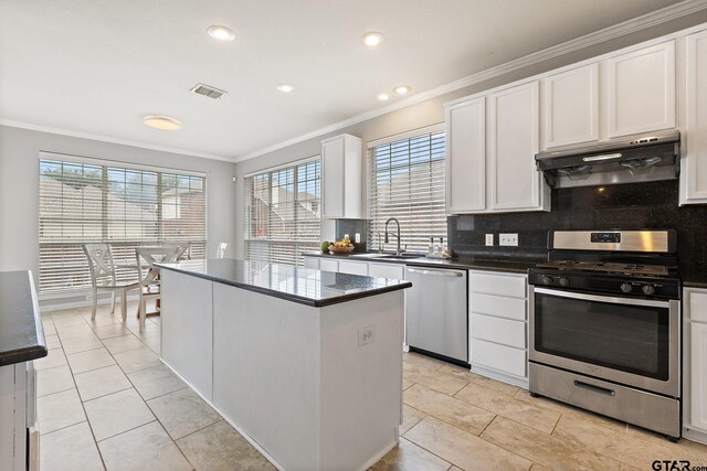 kitchen with crown molding, visible vents, under cabinet range hood, a sink, and appliances with stainless steel finishes
