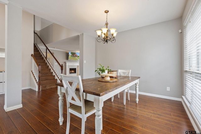 dining area featuring baseboards, a warm lit fireplace, a chandelier, and stairs
