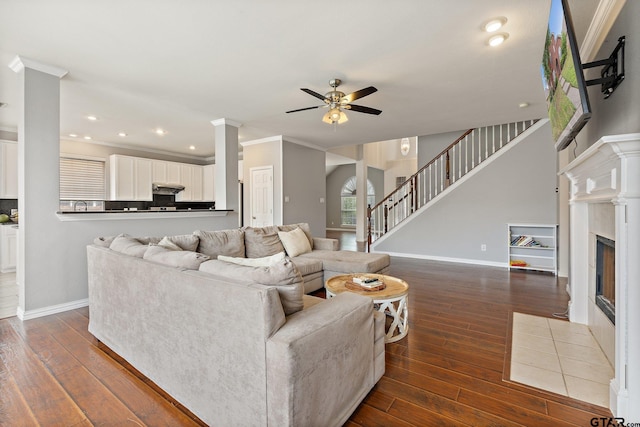 living area with a ceiling fan, baseboards, a fireplace with flush hearth, and dark wood-style floors