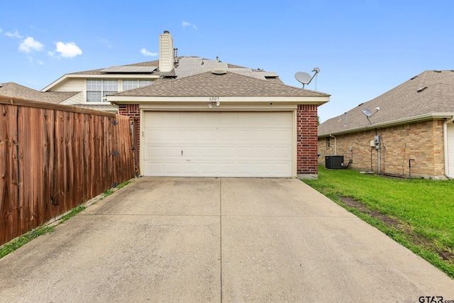 garage featuring fence, concrete driveway, and central AC