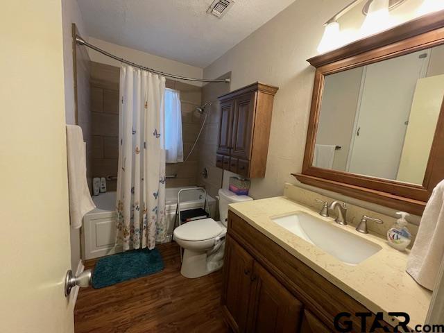 full bathroom featuring wood-type flooring, vanity, shower / bath combination with curtain, and toilet