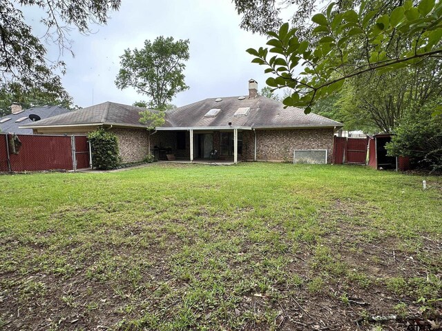 2203 S Williams Ave, Mount Pleasant, TX 75455 - back of property featuring a chimney, fence, a patio, a lawn, and brick siding