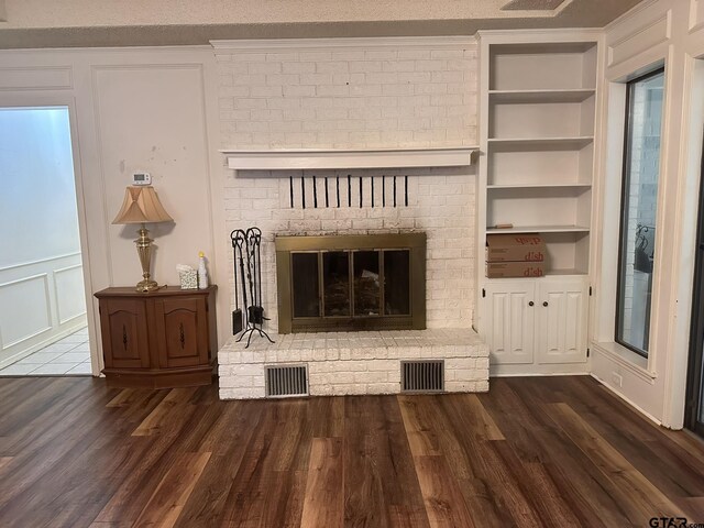 2203 S Williams Ave, Mount Pleasant, TX 75455 - unfurnished living room with a fireplace, wood finished floors, visible vents, and built in shelves