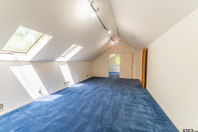 additional living space featuring visible vents, baseboards, a ceiling fan, lofted ceiling with skylight, and carpet flooring