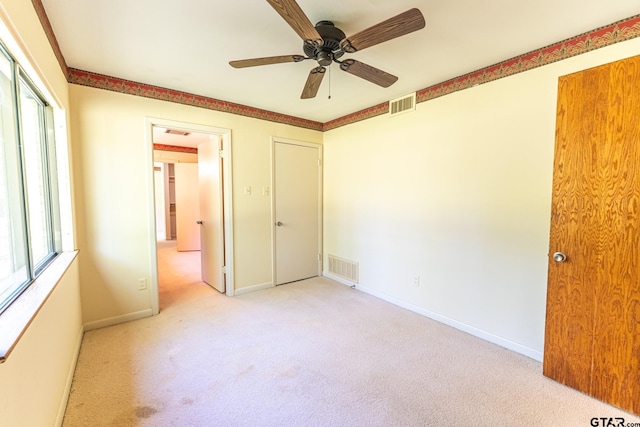 unfurnished bedroom featuring baseboards, a ceiling fan, visible vents, and carpet floors