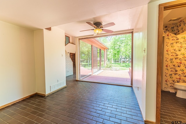 interior space with visible vents, baseboards, brick floor, and ceiling fan