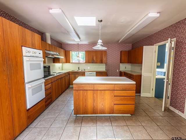 kitchen featuring brown cabinetry, white appliances, and wallpapered walls