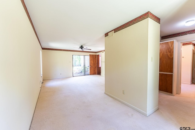 spare room with baseboards, light colored carpet, a ceiling fan, and crown molding