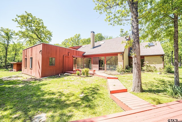 rear view of property featuring a chimney, brick siding, and a lawn
