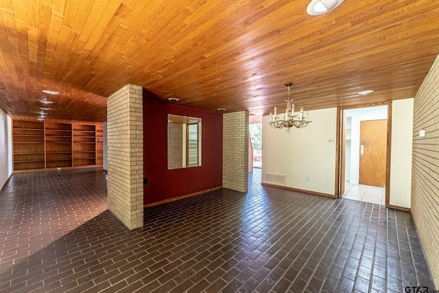 spare room featuring visible vents, built in features, an inviting chandelier, wood ceiling, and brick floor