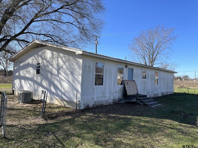 back of house featuring central AC unit and a yard