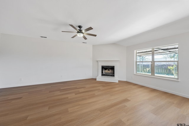 unfurnished living room with vaulted ceiling, ceiling fan, a brick fireplace, and light hardwood / wood-style floors