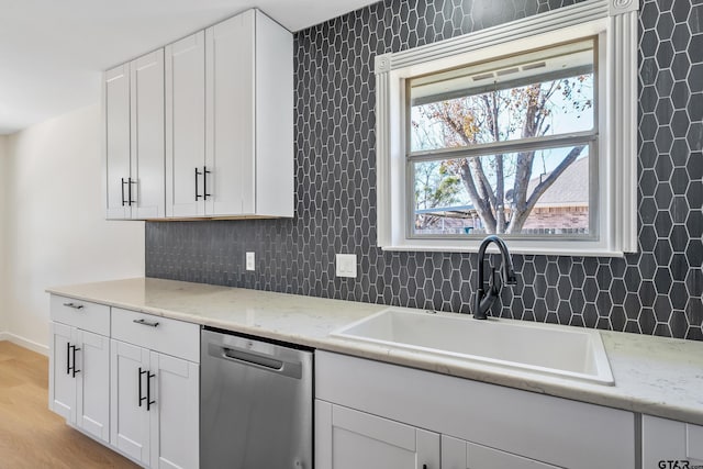 kitchen with sink, light stone countertops, white cabinets, and dishwasher