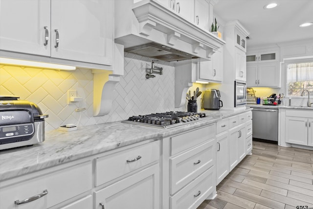 kitchen featuring decorative backsplash, light stone counters, stainless steel appliances, sink, and white cabinets