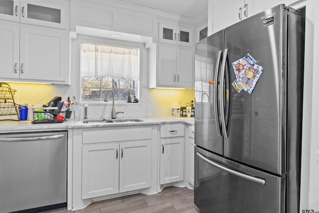 kitchen featuring white cabinetry, sink, stainless steel appliances, tasteful backsplash, and light hardwood / wood-style flooring