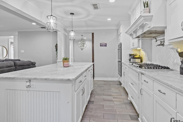 kitchen with white cabinets, appliances with stainless steel finishes, a kitchen island, and pendant lighting