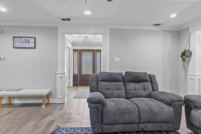 living room featuring light hardwood / wood-style floors, decorative columns, and crown molding