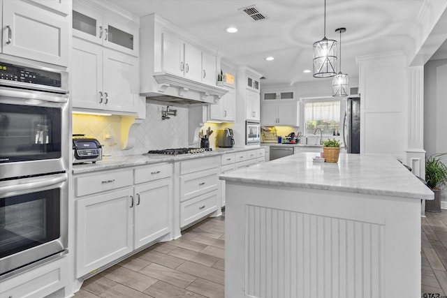 kitchen featuring white cabinetry, a center island, custom range hood, and appliances with stainless steel finishes