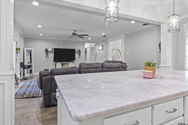 kitchen with ornamental molding, ceiling fan, pendant lighting, a center island, and white cabinetry