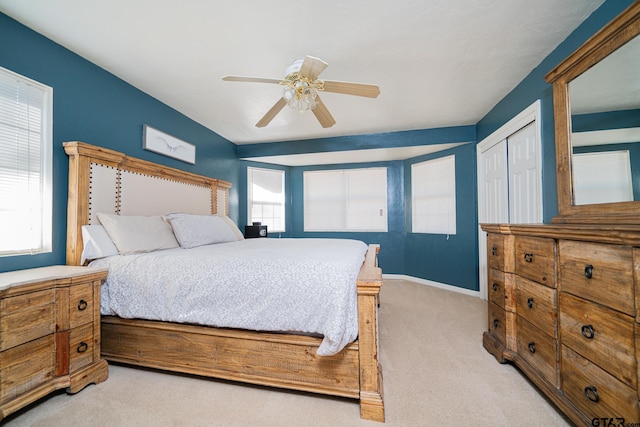 bedroom featuring ceiling fan, multiple windows, a closet, and light carpet