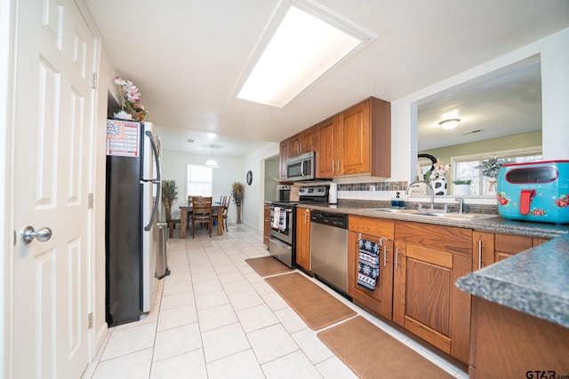 kitchen with plenty of natural light, sink, light tile patterned floors, and stainless steel appliances