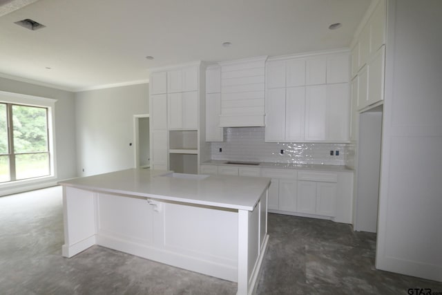 11941 Gillian Ct, Tyler, TX 75703 - kitchen with crown molding, decorative backsplash, a kitchen island, white cabinetry, and cooktop