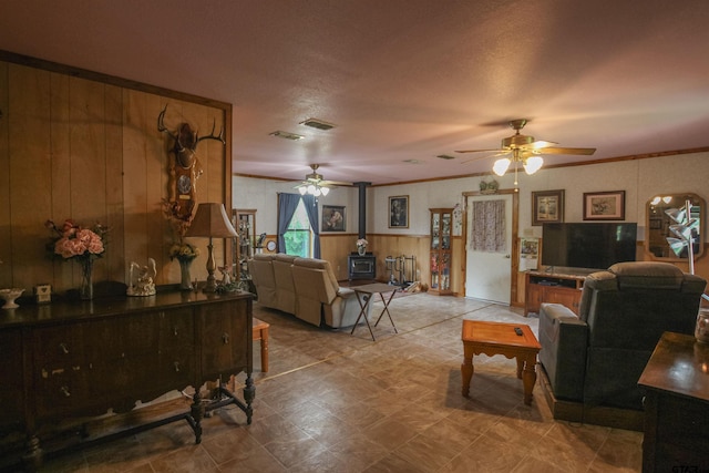2391 Fm 16 W, Tyler, TX 75706 - living area with a wood stove, ceiling fan, wooden walls, and crown molding