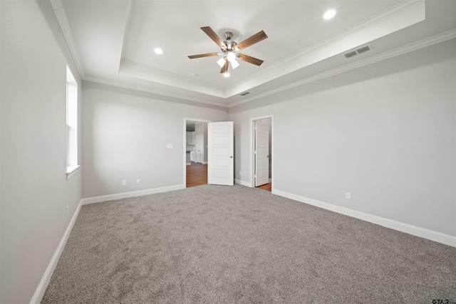 unfurnished bedroom with ornamental molding, a tray ceiling, carpet flooring, and ceiling fan