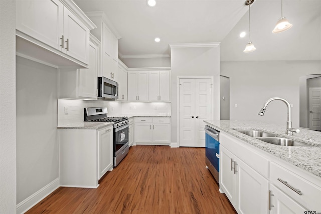 kitchen featuring white cabinetry, sink, appliances with stainless steel finishes, hardwood / wood-style floors, and hanging light fixtures